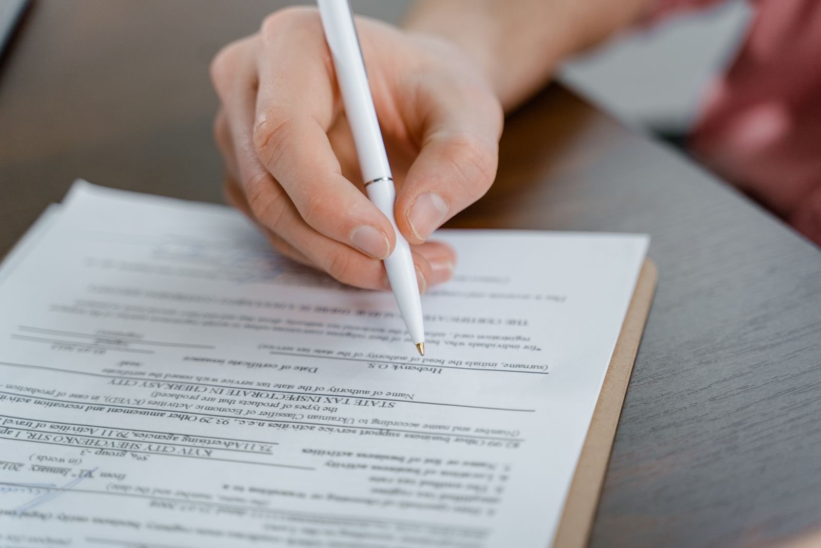 Un devis se lit poste par poste Main tenant un stylo au-dessus d'un document imprimé, en gros plan.